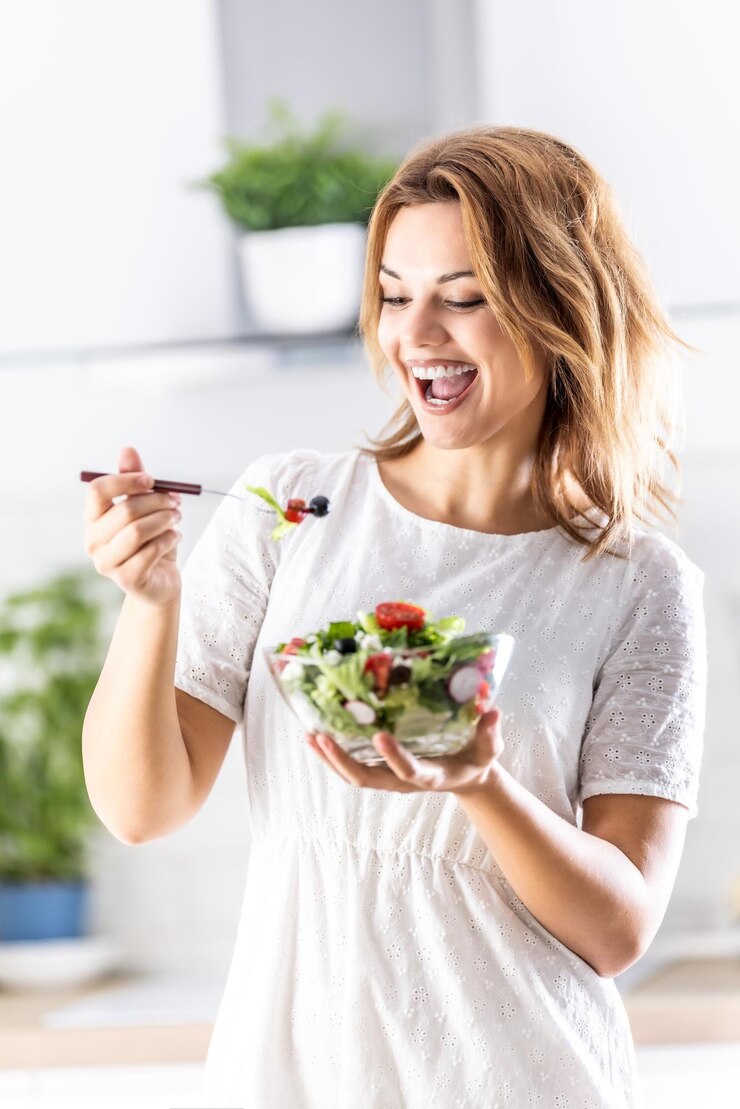 Eine schöne junge Dame genießt es, einen gesunden Salat zu essen.