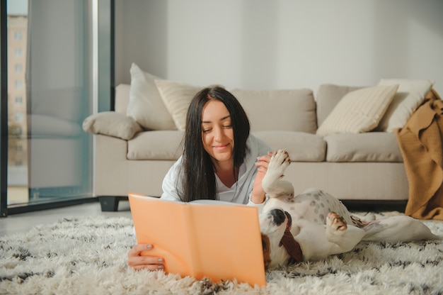 Eine schöne junge Frau, die ihr Lieblingsbuch mit ihrem Hund liest