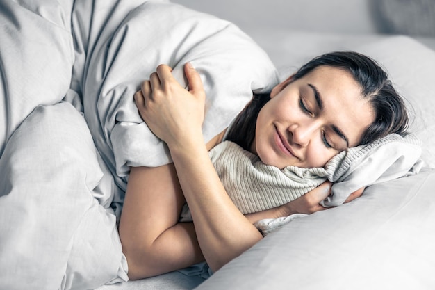 Eine schöne junge Frau schläft in einem weißen Bett