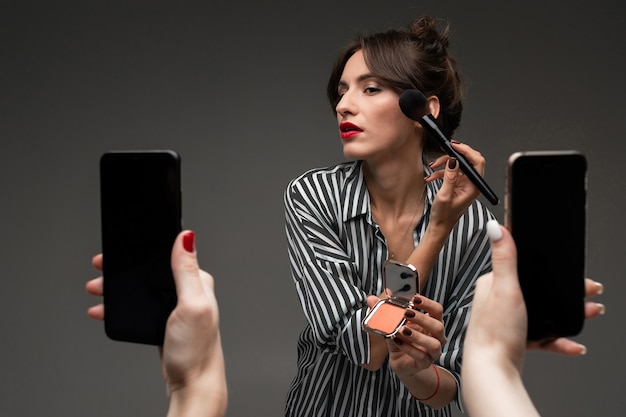 Eine schöne junge kaukasische Frau mit dunklem Haar und hübschem Gesicht machen Make-up und Selfie