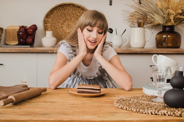 Eine schöne Konditorin oder Hausfrau sitzt in der Küche und sieht sich das Dessert an