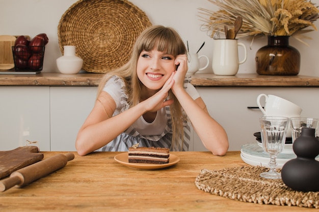 Eine schöne Konditorin oder Hausfrau sitzt mit Dessert in der Küche und sieht nachdenklich aus