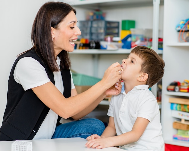 Eine schöne Logopädin beschäftigt sich mit dem Jungen und bringt ihm die richtige Aussprache und kompetente Sprache bei.