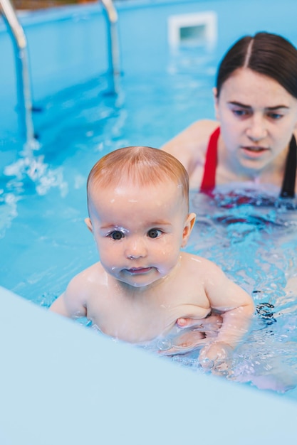 Eine schöne Mutter bringt ihrem kleinen Sohn bei, wie man im Pool schwimmt. Ein Kind vergnügt sich mit seiner Mutter im Wasser. Entwicklung des Kindes Erster Schwimmunterricht für Kinder