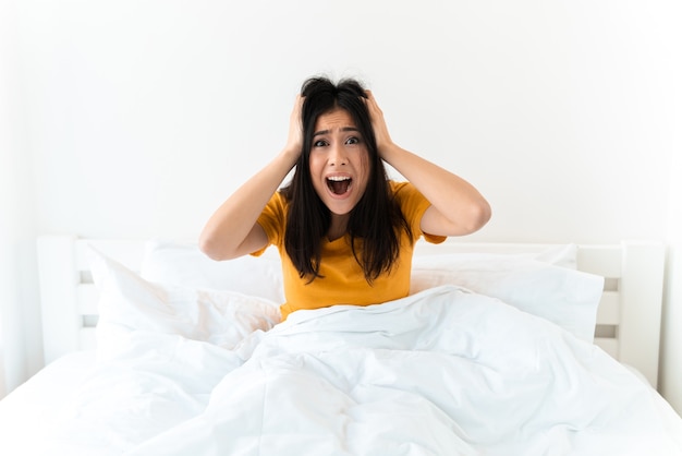 eine schöne schreiende verängstigte junge frau im bett zuhause zu hause.