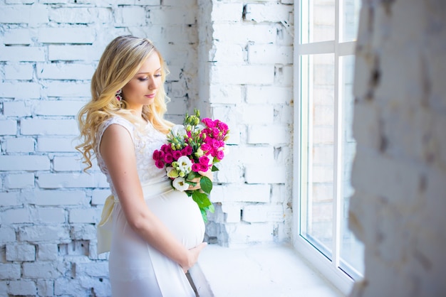 Eine schöne schwangere Frau mit einem Blumenstrauß wartet auf das Baby Schwangerschaft