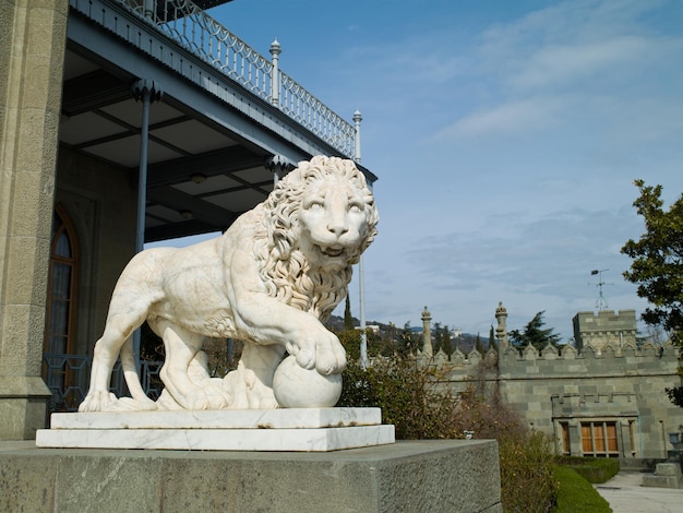 Eine schöne Skulptur eines Löwen auf einem Hintergrund von Bergen und dem Palast