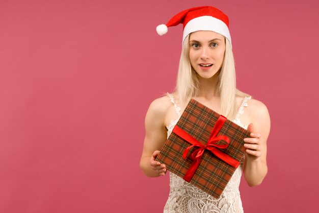 Eine schöne sportliche Frau in einem Neujahrshut und einem weißen Kleid, halten in den Händen Geschenke