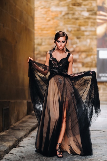Eine schöne stilvolle Braut in einem schwarzen Kleid geht durch Florenz, ein Model in einem schwarzen Kleid in der Altstadt von Italien.