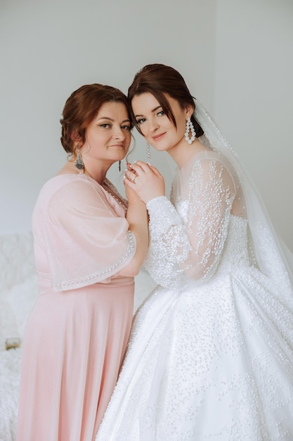 Eine schöne und glückliche Mutter und ihre Tochter die Braut stehen nebeneinander der beste Tag für Eltern zärtliche Momente auf der Hochzeit