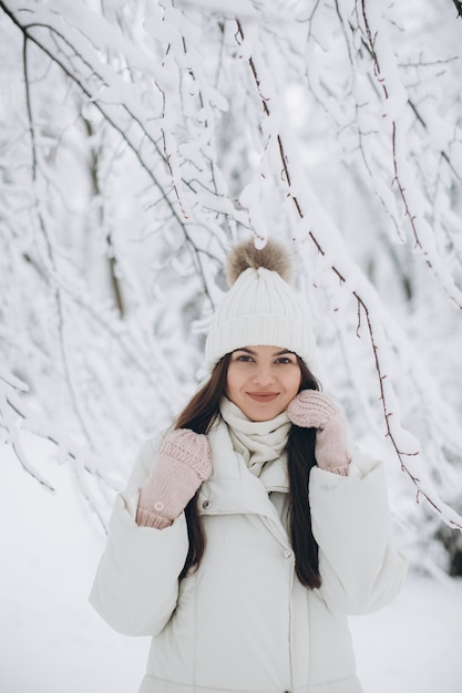 Eine schöne und Modefrau in der weißen warmen Kleidung gehend in schneebedecktes Wetter.