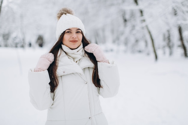 Eine schöne und Modefrau in der weißen warmen Kleidung gehend in schneebedecktes Wetter.