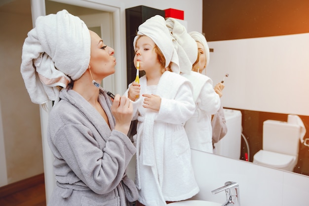 Eine schöne und stilvolle Mutter lehrt, die Zähne ihrer kleinen Tochter zu bürsten
