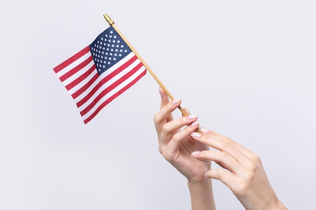 Eine schöne weibliche Hand hält eine amerikanische Flagge auf einem weißen Hintergrund