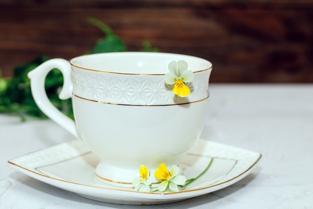 Eine schöne weiße Tasse mit einem goldenen Rand, der mit Blumen verziert ist. Gestaltung von Geschäftskonten.