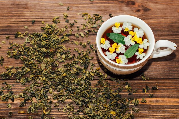 Eine schöne weiße tasse mit einem goldenen rand verziert mit blumen, kräutergrüner gesunder tee. gestaltung von geschäftskonten.