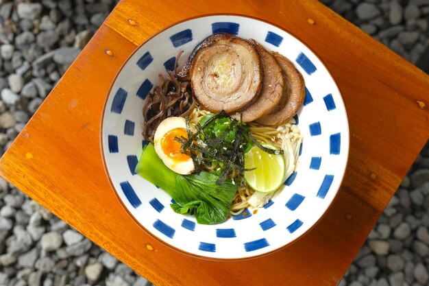 Foto eine schüssel gebratener ramen auf dem tisch rindfleischrolle eine halbe gekochte ei-pilz-nori-lime als topping