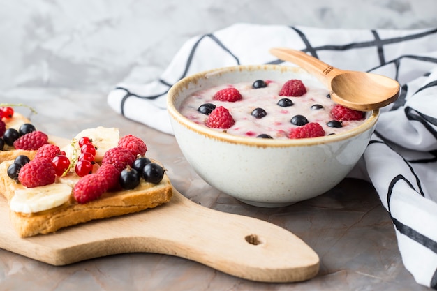 Eine Schüssel Haferflocken mit Beeren neben einem Brett mit Sandwiches