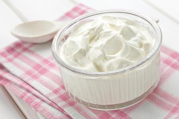 Foto eine schüssel joghurt mit einem löffel auf einem rosa karierten tuch.