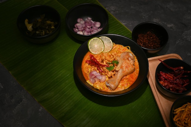 Eine Schüssel Khao Soi Kai oder cremig-würziges gelbes Curry mit Hähnchenschenkel