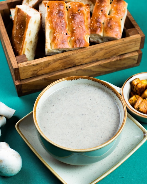 Eine Schüssel Knoblauchbrot neben einer Schüssel weißer Suppe.