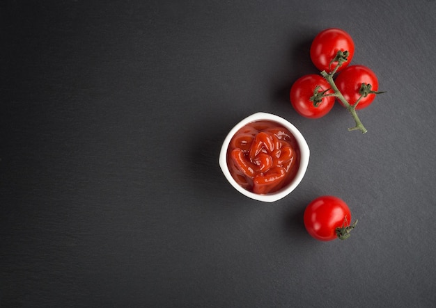 Eine Schüssel mit Basilikum Ketchup und Tomaten auf schwarzem Hintergrund Scoop Ketchup mit einem Löffel