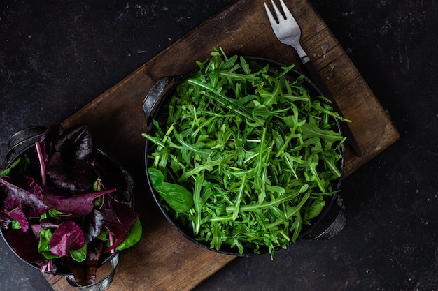 Eine Schüssel mit grünem Salat neben einem Glas rotem und violettem Salat.