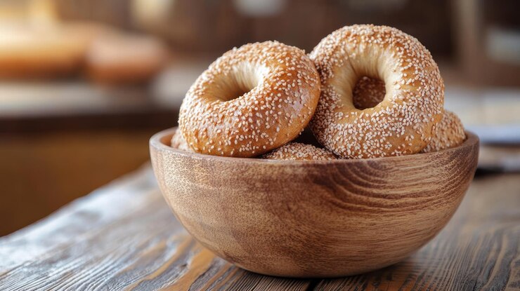 Eine Schüssel mit Sesamkörnern gibt es sechs Bagels in der Schüssel, die Bagels sind alle unterschiedlicher Größe.