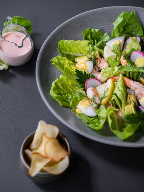 Foto eine schüssel salat mit einer schüssel kartoffelchips daneben.