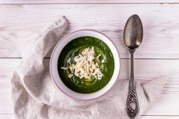 Eine Schüssel Spinatcremesuppe auf weißem Holzhintergrund