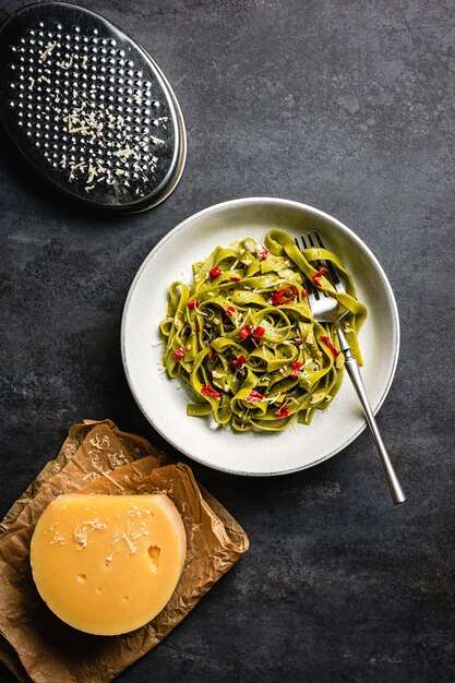 Eine Schüssel Tagliatelle-Spinat-Nudeln mit rotem Chili, geriebenem Käse und Olivenöl.