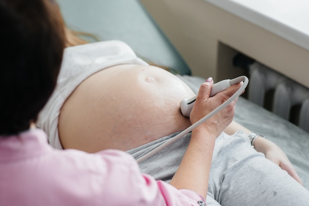 Eine schwangere Frau hat in der Klinik einen Ultraschall des Abdomens in Nahaufnahme. Ärztliche Untersuchung