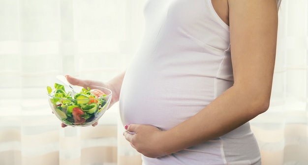 Eine schwangere Frau isst einen Salat mit Gemüse