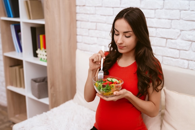 Eine schwangere Frau isst einen Salat.