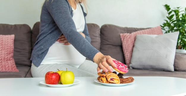 Eine schwangere Frau isst einen süßen Donut. Selektiver Fokus