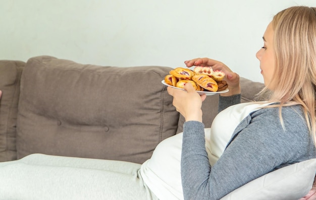 Eine schwangere Frau isst einen süßen Donut. Selektiver Fokus
