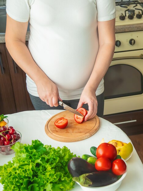 Eine schwangere Frau isst Gemüse und Obst