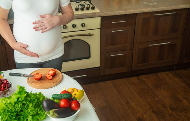 Eine schwangere Frau isst Gemüse und Obst