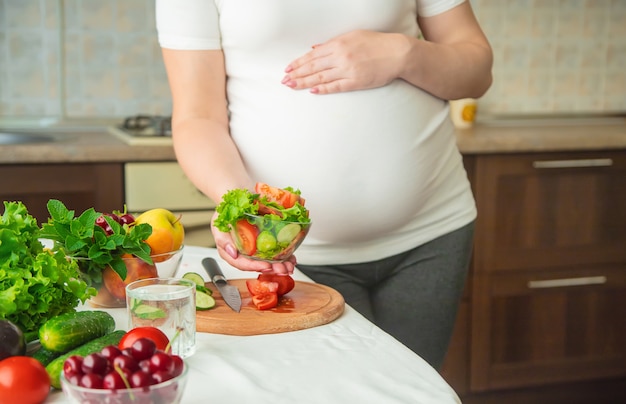 Eine schwangere Frau isst Gemüse und Obst