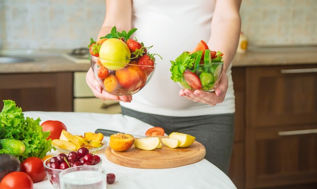 Eine schwangere Frau isst Gemüse und Obst