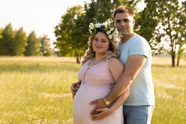 Eine schwangere Frau mit ihrem Ehemann auf einem Hintergrund eines Feldes