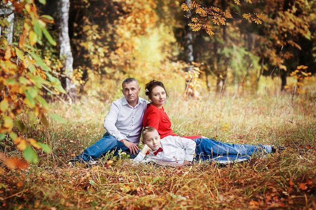 Eine schwangere Frau mit ihrem Mann und ihrem Sohn in einem Herbstpark