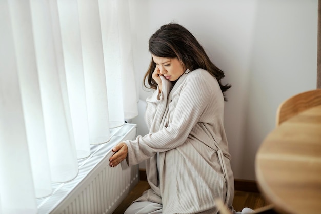 Eine schwangere Frau prüft den Heizkörper, ob er warm ist