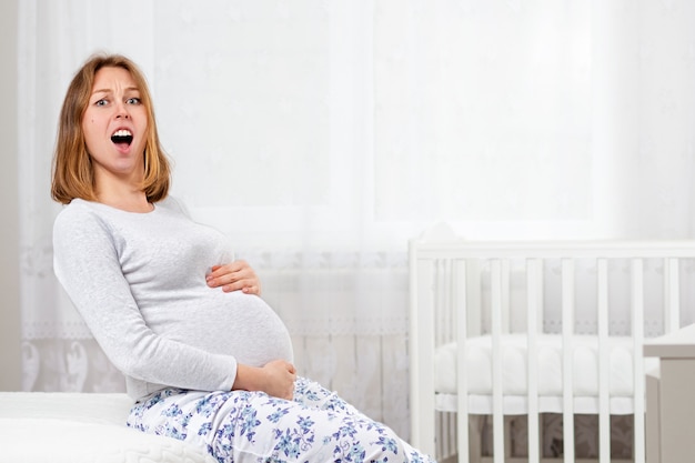 Eine schwangere Frau schreit, während sie ihren Bauch hält