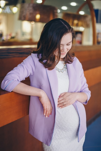 Eine schwangere Frau streichelt ihren Bauch. Ein Mädchen, das auf ein Kind wartet, geht in ein Einkaufszentrum. Das Konzept eines gesunden Lebensstils, IVF, Mode für Schwangere, Kinder