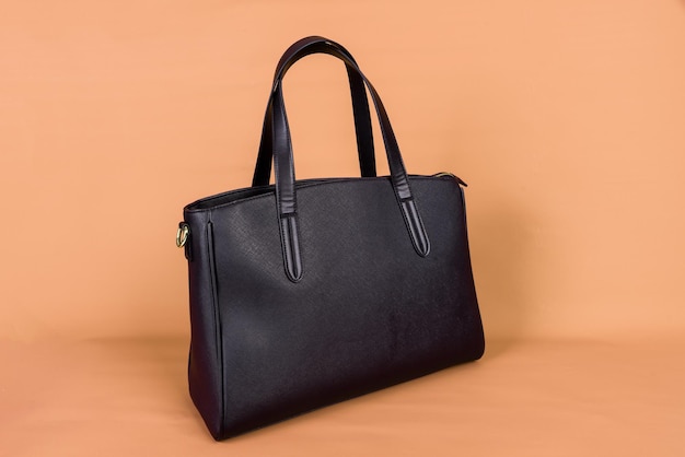 Eine schwarze Ledertasche auf einem orangefarbenen Hintergrund