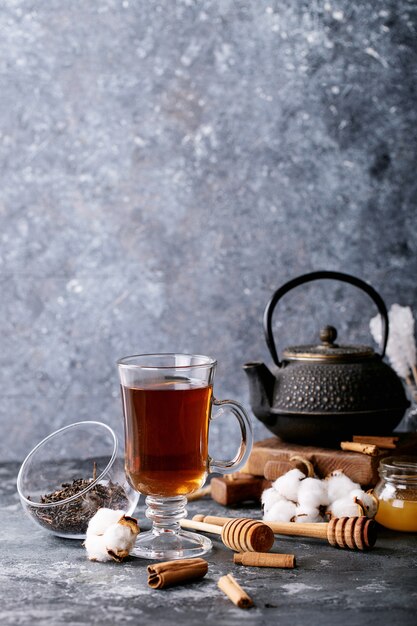 Eine schwarze Metallteekanne und eine Tasse Tee in einer Glasschale