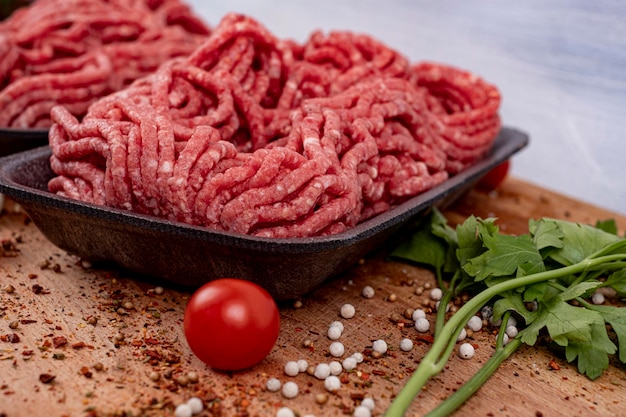 Eine schwarze Schüssel Hackfleisch mit einem Bündel Kräuter auf einem Holztisch.