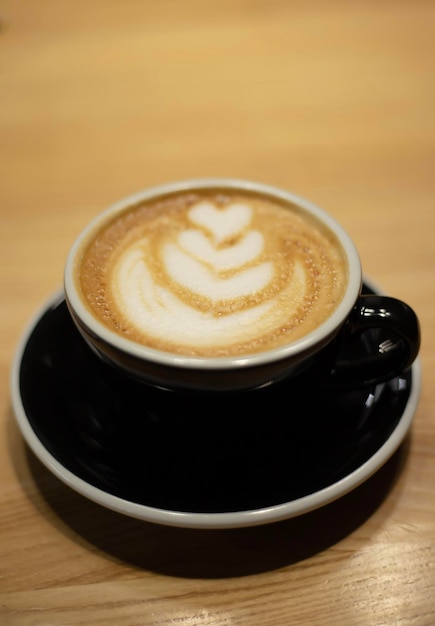 Eine schwarze Tasse Kaffee mit einem Herzmuster auf der Oberseite.