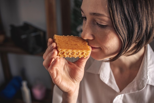 Eine Seifenmacherin hält eine handgefertigte Honigseife in ihren Händen, eine Menge verschiedener geschnittener Stücke.